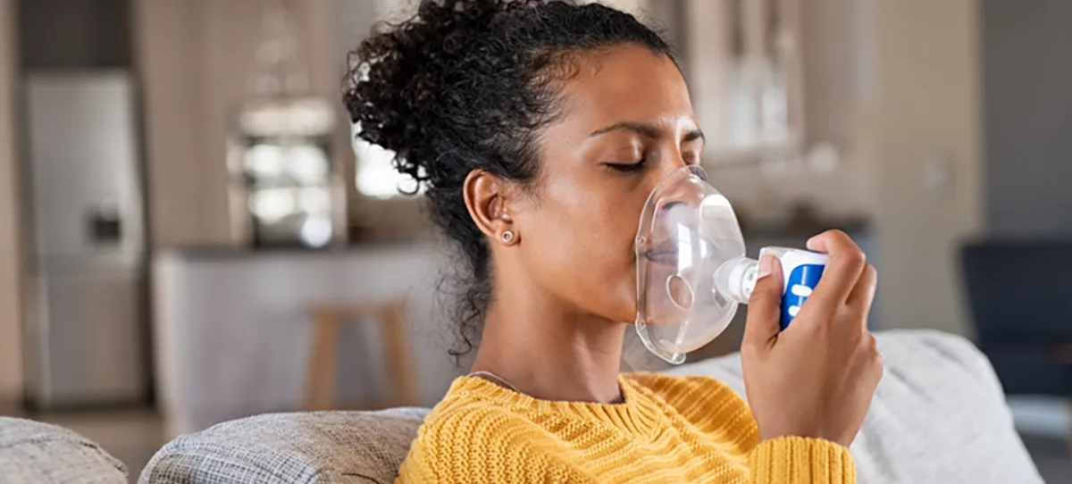woman sitting on a couch using an inhaler